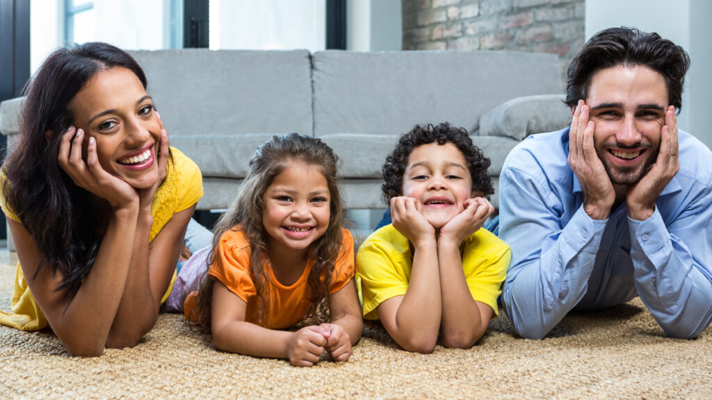 family laying side by side on a professionally cleaned carpet