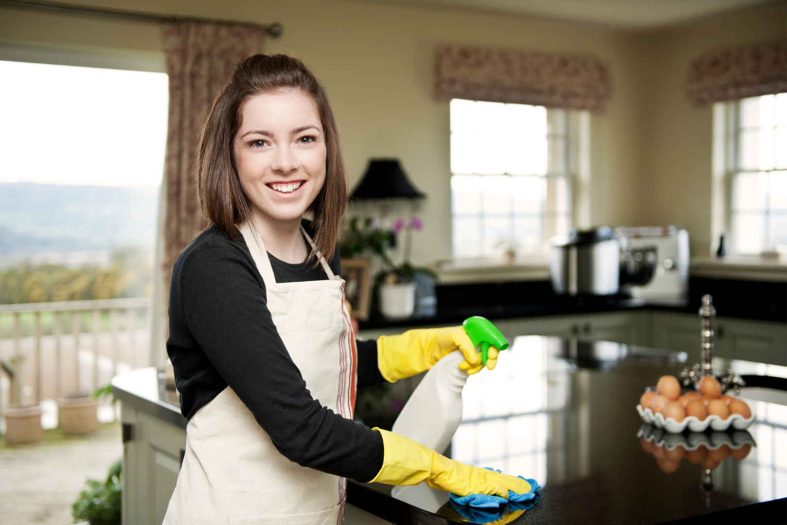 woman wearing apron cleaning counter and smiling