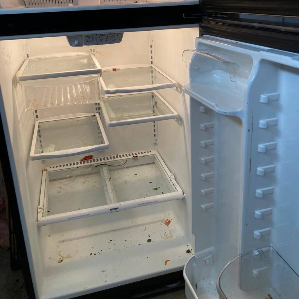 A refrigerator with dirty glass shelves, visible stains, and food residue before a deep cleaning service.