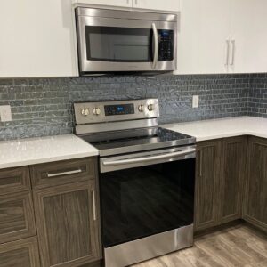 A fully cleaned stainless steel oven and microwave with a spotless backsplash and countertop.