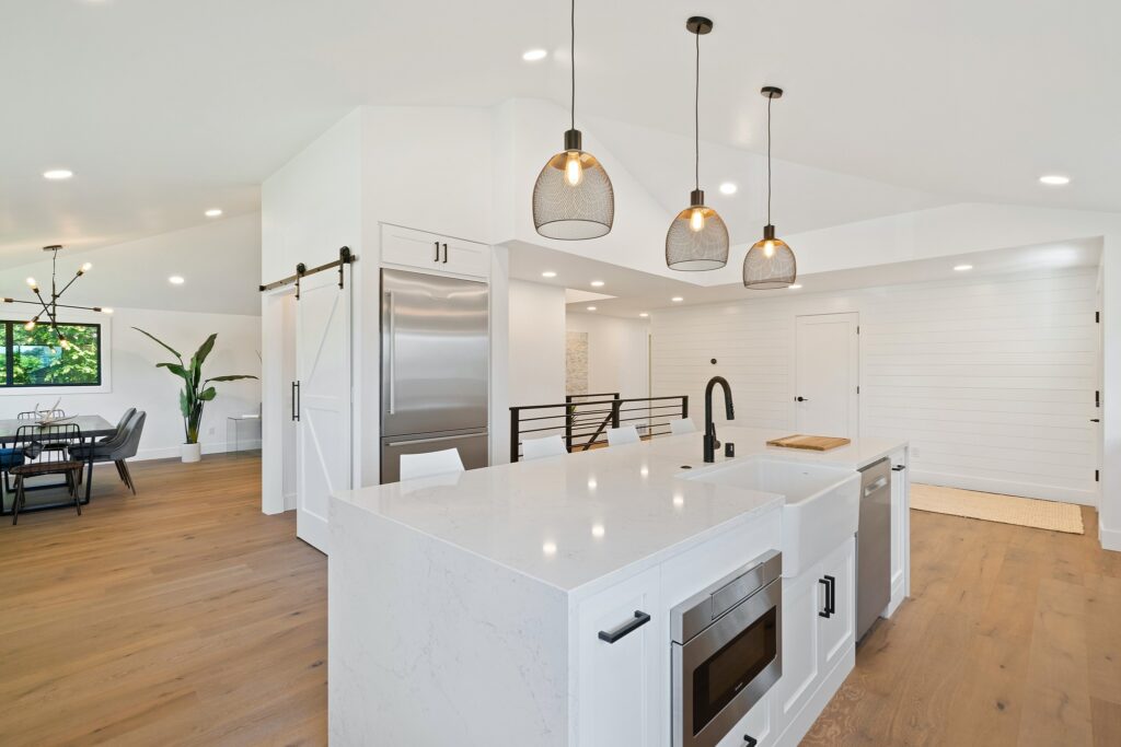 : A bright, spacious kitchen with white cabinets, pendant lighting, and an island with a modern sink.